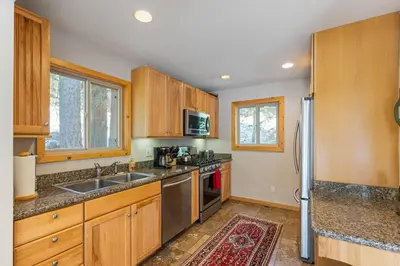 a kitchen with wooden cabinets and a stainless steel refrigerator at Trailside - Alpine Meadows 6 Bedroom with Private Hot tub in Alpine Meadows