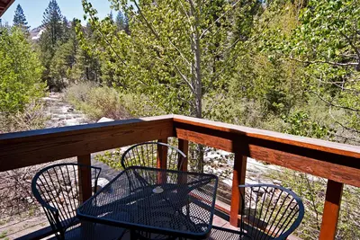 a balcony with two chairs and a view of a forest at Creek Side- 4 Primary Suites, Hot Tub, Shuttle to Slopes, Pet Friendly in Olympic Valley