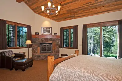 a bedroom with a large bed and a fireplace at Bullshead Lodge- Luxury Estate, 4 Acres on River, Hot Tub, Minutes from the Slopes! in Olympic Valley