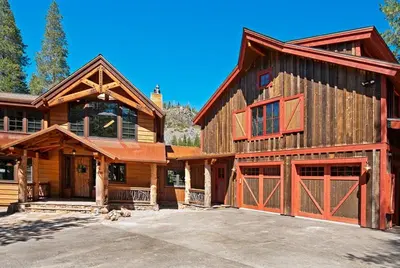 a large wooden house with two garage doors at Bullshead Lodge- Luxury Estate, 4 Acres on River, Hot Tub, Minutes from the Slopes! in Olympic Valley
