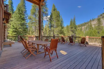 a wooden deck with a table and chairs on it at Bullshead Lodge- Luxury Estate, 4 Acres on River, Hot Tub, Minutes from the Slopes! in Olympic Valley