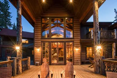 a log cabin with a deck with chairs and lights at Bullshead Lodge- Luxury Estate, 4 Acres on River, Hot Tub, Minutes from the Slopes! in Olympic Valley