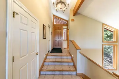 a hallway with a white door and a chandelier at Eagles Nest by Tahoe Getaways - Pet Friendly with Hot Tub, Pool Table & Shuttle to Slopes in Olympic Valley