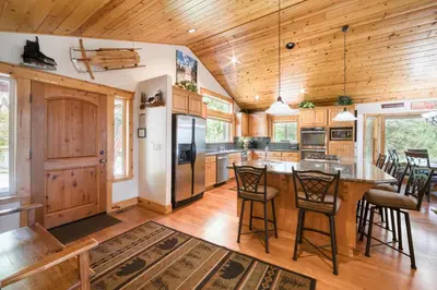 a kitchen with wooden ceilings and a large island with bar stools at Fawn View by Tahoe Getaways - Spacious 5 BR w Pool Table-Short Drive to Northstar in Tahoe Vista