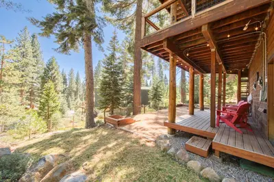 a wooden porch of a cabin with red chairs on it at Fawn View by Tahoe Getaways - Spacious 5 BR w Pool Table-Short Drive to Northstar in Tahoe Vista
