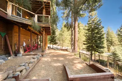 a walkway next to a log cabin with trees at Fawn View by Tahoe Getaways - Spacious 5 BR w Pool Table-Short Drive to Northstar in Tahoe Vista