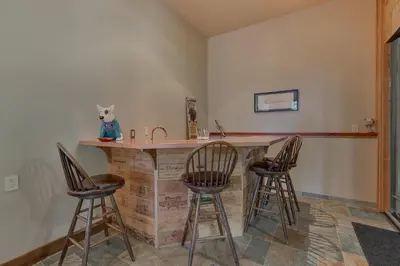 a kitchen with a counter with three bar stools at Gray Bear Lake View Estate - Stunning Cabin w 4 Master Suites, Private Hot Tub! in Carnelian Bay