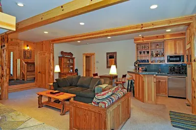 a living room with a couch and a kitchen at Sierra Crest at Palisades Tahoe - Secluded Luxury 5BR 5 BA w Wood Fireplace in Olympic Valley