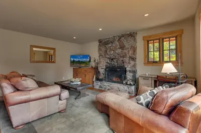 a living room with two couches and a stone fireplace at Summit Solitude at Palisade Tahoe - Charming 5BR w Foosball & Shuffleboard Table & Pet Friendly in Olympic Valley