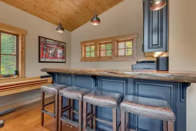 a kitchen with blue cabinets and bar stools at Summit Solitude at Palisade Tahoe - Charming 5BR w Foosball & Shuffleboard Table & Pet Friendly in Olympic Valley