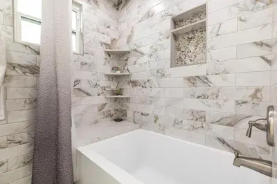 a bathroom with white marble walls and a tub at Beach Haven Lakefront - On a Sandy Beach with Guest House in Kings Beach