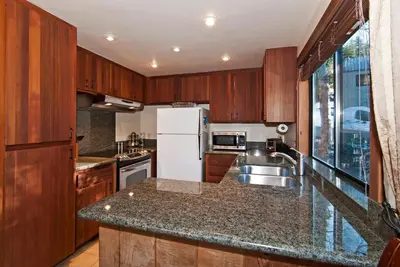 a kitchen with wooden cabinets and a white refrigerator at Alpine Darling- Hot Tub- Pet Friendly- 3 Minute Drive to Palisades Tahoe in Alpine Meadows
