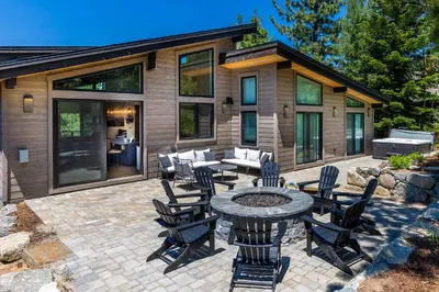 a patio with a table and chairs in front of a house at Harmony at Tahoe Donner - Ultra Modern 4 BR, Hot Tub, Game Room, Amenity Access in Truckee