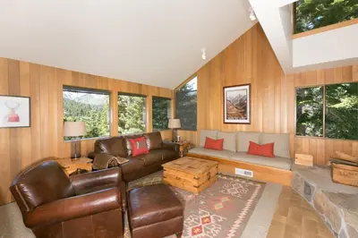 a living room with brown leather furniture and windows at Juniper at Alpine - Private Hot tub, Pet Friendly & Free Shuttle to Slopes in Olympic Valley