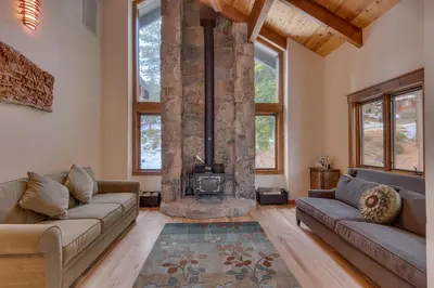 a living room with two couches and a stone fireplace at Kings Way Lake View by Tahoe Getaways - Spacious 4 BR w Private Hot Tub, Pool Table! in Tahoe Vista