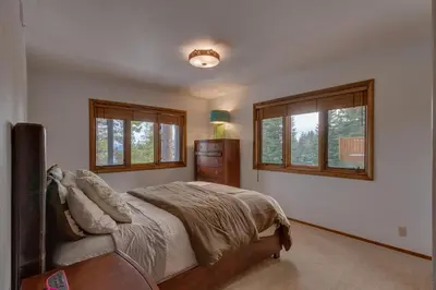 a bedroom with a bed and two windows at Kings Way Lake View by Tahoe Getaways - Spacious 4 BR w Private Hot Tub, Pool Table! in Tahoe Vista
