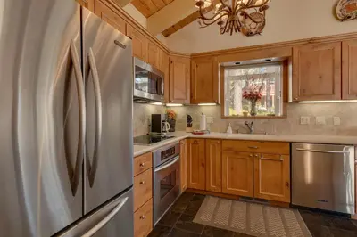 a kitchen with wooden cabinets and a stainless steel refrigerator at Lake Haven at Dollar Point - Spacious 4 BR w Lake Views, Sauna, Near Ski Resorts! in Tahoe City