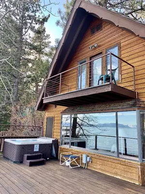 a house with a deck with a large window at Lakeside Escape - Beautiful Lakefront, Pier, Wood Fireplace, Private Hot Tub in Tahoe Vista