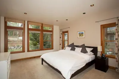 a bedroom with a bed with white sheets and windows at Look Out Lodge - On North Shore w Lake View, Hot Tub, Pool Table and Pet Friendly in Kings Beach