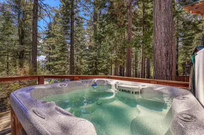 a hot tub on a deck with trees in the background at Lupine Lodge at Tahoe Park on the West Shore - Hot Tub, Beach Access, Near Ski Resorts! in Tahoe City
