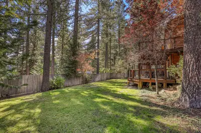 a yard with a wooden fence and a house at Lupine Lodge at Tahoe Park on the West Shore - Hot Tub, Beach Access, Near Ski Resorts! in Tahoe City