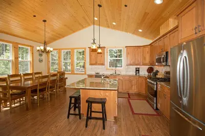 a kitchen with wooden cabinets and a table with chairs at Sans Souci Terrace on the West Shore- 4 BR Cabin, Avail as a Ski Lease, Near Skiing! in Homewood