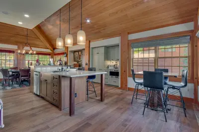 a kitchen with wooden floors and a large island with bar stools at Skidder - Luxury 3500 sqft - Northstar 4BR w Game Room, Sauna, & HOA Amenities in Truckee