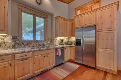 a kitchen with wooden cabinets and a stainless steel refrigerator at Skislope Manor - Spacious Tahoe Donner 4 BR with Gorgeous Home Theater and Hot Tub in Truckee