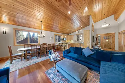 a living room with a blue couch and a kitchen at Skislope Manor - Spacious Tahoe Donner 4 BR with Gorgeous Home Theater and Hot Tub in Truckee