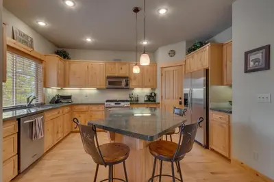 a kitchen with wooden cabinets and a table with chairs at High Altitude at Tahoe Donner - Huge 4 BR with Private Hot Tub, Pool Table, Ping Pong, HOA Amenities in Truckee