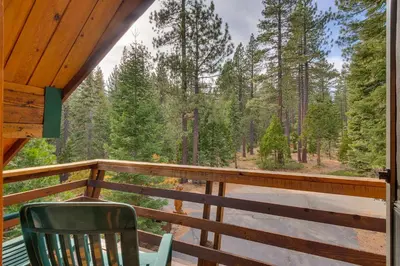 a deck with a chair and a view of the woods at Cozy Wood Cabin- Updated- Hot Tub- Fireplace- Backs to Forest in Carnelian Bay