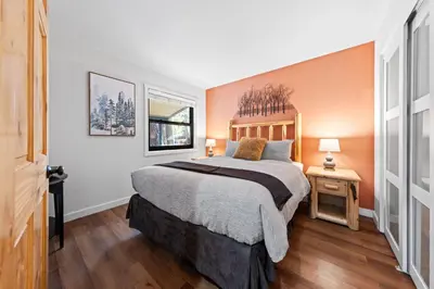 a bedroom with a large bed with an orange wall at Sandy Cove on the North Shore -Lakeside Cottage with Pier Beach, and HOA Amenities in Tahoe Vista