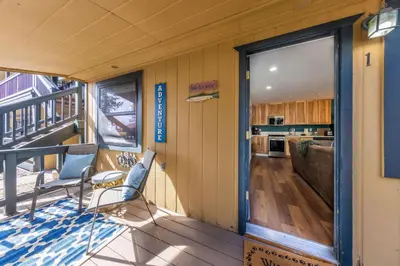 a room with a balcony with chairs and a kitchen at Sandy Cove on the North Shore -Lakeside Cottage with Pier Beach, and HOA Amenities in Tahoe Vista