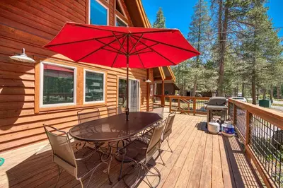 a wooden deck with a table with chairs and an umbrella at Olympic Valley Hideaway - Newly Remodeled Cabin with Private Hot Tub in Olympic Valley