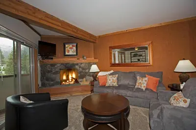 a living room with a couch and a fireplace at Palisades Tahoe Ski Condo by Tahoe Getaways - Remodeled 2 BR, Walking Distance to Lifts & Village in Olympic Valley