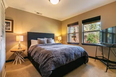 a bedroom with a bed and a desk and two windows at Pinecrest at Winter Creek- Cozy Cabin w Hot Tub, Walk To Downtown Truckee in Truckee