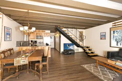 a living room with a dining room table and a staircase at Pineland Chalet in Tahoe City - Classic Cabin Wood Fireplace Dog Friendly in Tahoe City