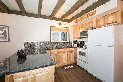 a kitchen with a white refrigerator and wooden cabinets at Pineland Chalet in Tahoe City - Classic Cabin Wood Fireplace Dog Friendly in Tahoe City