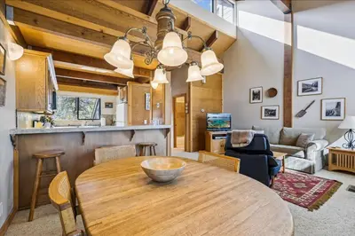 a kitchen and living room with a wooden table at Rocky Point # 4 - 2 BR Northstar Condo, Shuttle to Slopes, HOA Amenities! in Truckee