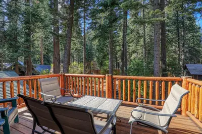 a wooden deck with two chairs and a table at Secret Garden Lodge - 4BR Walking Distance to the Lake, Hot Tub, Close to Ski Resorts! in Carnelian Bay