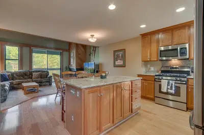a kitchen with wooden cabinets and a living room at Silver Strike #2- Walk to Village- Ski Shuttle to Lifts in Truckee