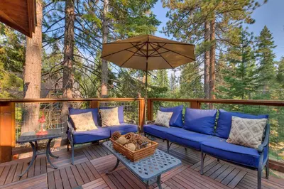 a deck with blue couches and an umbrella at Tahoe Rim Retreat - Spacious 4BR with Pool Table and Private Hot Tub - Pet Friendly! in Kings Beach