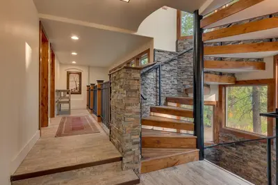 a hallway with wooden stairs and a stone wall at Tahoe Rim Retreat - Spacious 4BR with Pool Table and Private Hot Tub - Pet Friendly! in Kings Beach