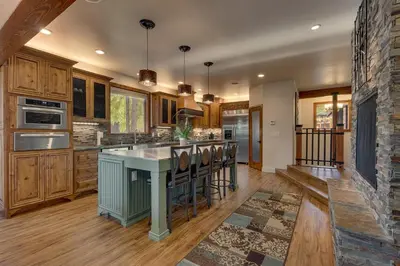 a kitchen with wooden cabinets and a stone wall at Tahoe Rim Retreat - Spacious 4BR with Pool Table and Private Hot Tub - Pet Friendly! in Kings Beach