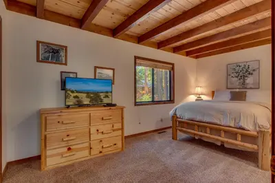 a bedroom with a bed and a tv on a dresser at Tahoe Woods by Tahoe Getaways - Pet Friendly Tahoe Park Cabin w Hot Tub, Fireplace, Near Skiing! in Tahoe City