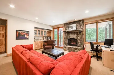 a living room with a red couch and a fireplace at Truckee Timbers at Gray's Crossing by Tahoe Getaways - 4BR w Hot Tub, Ping Pong & EV in Truckee