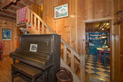 a wooden staircase in a room with a piano at Ward Creek Retreat - Cozy Old Tahoe Cabin w Short Drive to Ski Resorts Pet Friendly in Tahoe City