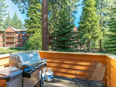 a grill and a chair on a deck with trees at 252 McCloud Upper level unit in Incline Village