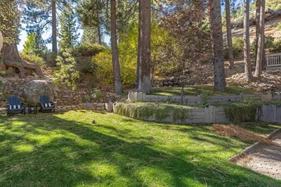 a yard with a stone wall and chairs and trees at Fabulous Views Of Lake Tahoe in Crystal Bay