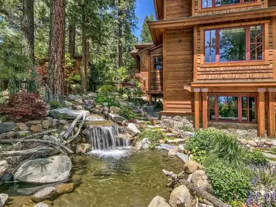 a log house with a pond and waterfall in front of it at A Touch Of Tuscany In a Lake Tahoe Estate in Incline Village